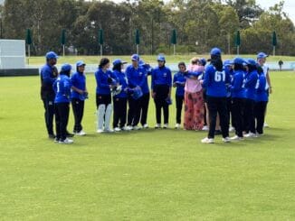 Afghan women's cricket team adjusting their caps while standing on the field.