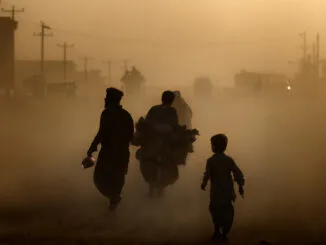 Kabul Air Pollution Crisis: Climate Change, Fuel Quality, and Traffic Worsen Air Quality A hazy street in Kabul, Afghanistan, showing people walking and cycling through thick air pollution, highlighting severe environmental conditions.