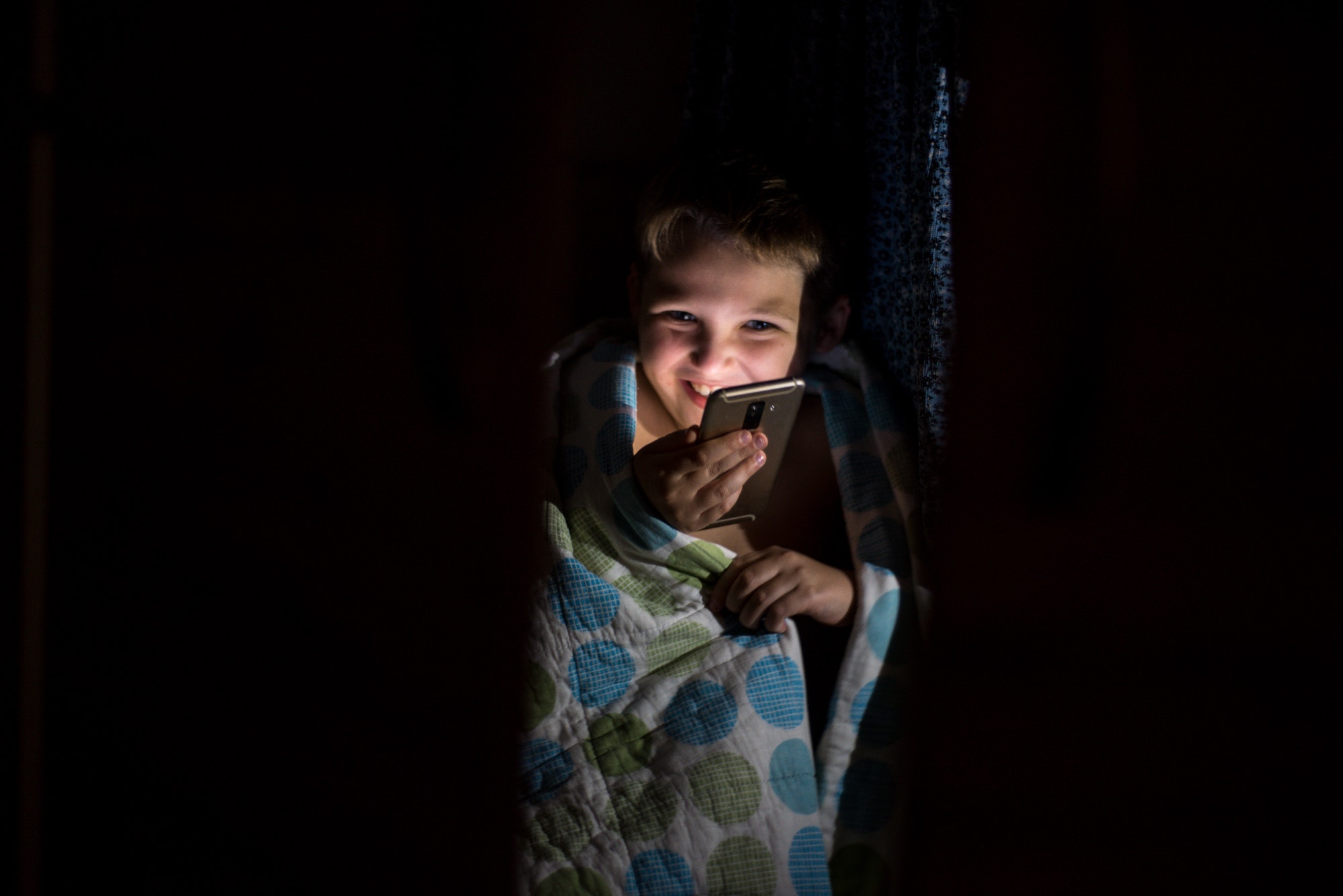 boy hid from his mother in the closein the wardrobe at night, plays with the phone
